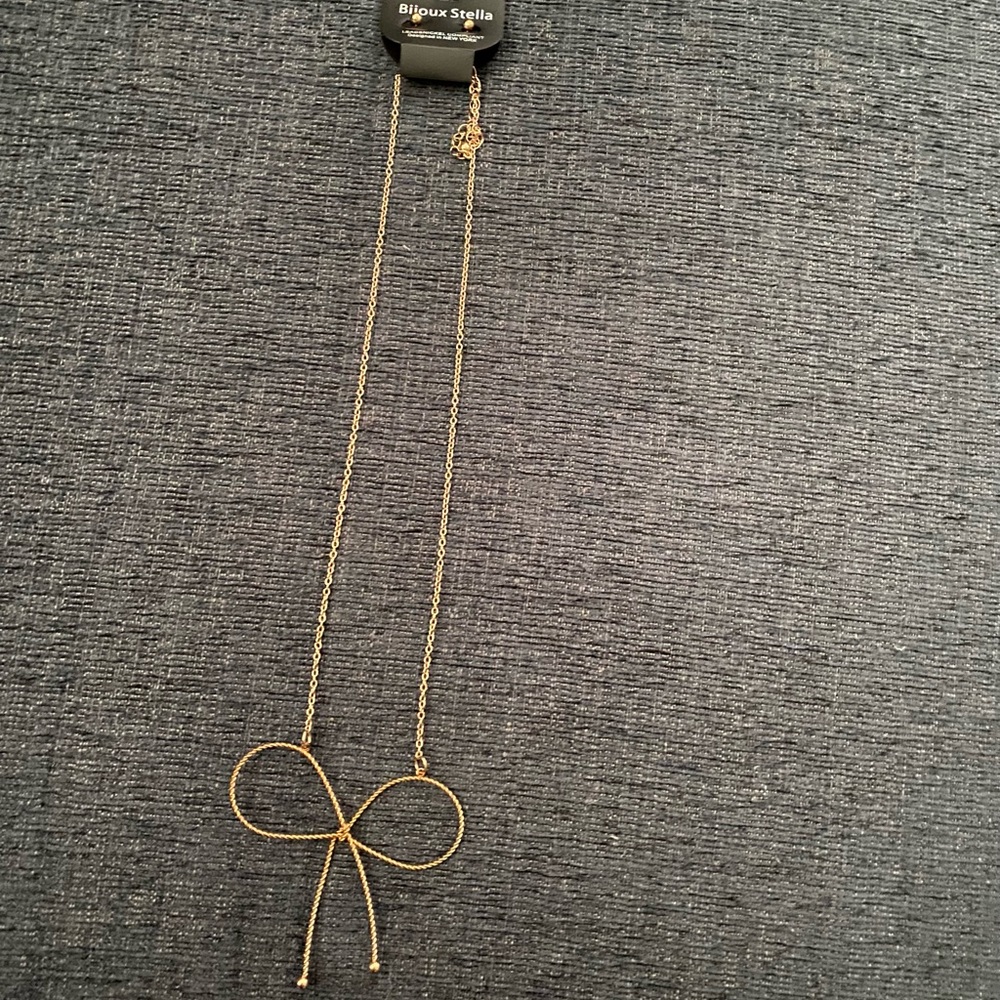 Gold bow necklace with gold ball earrings.